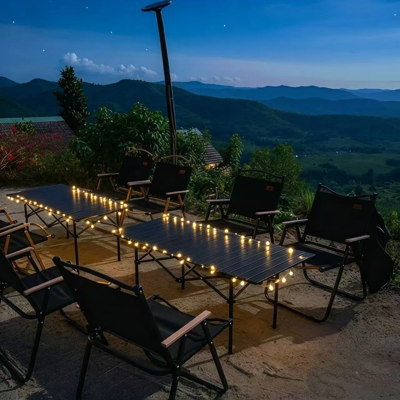 String lights on table overlooking mountains at dusk